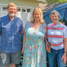 Three people standing outside smiling and posing for the picture